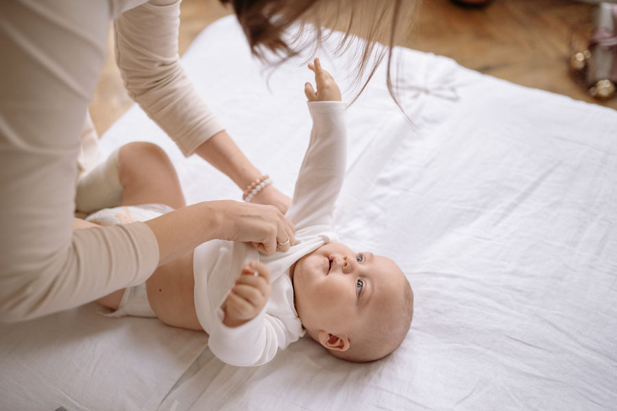 Parent dressing a baby in a long-sleeve onesie for a cold Australian winter night`