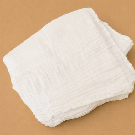 Stack of white cloth diapers on a brown background